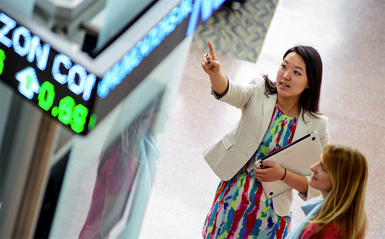 Schreyer Scholar Emily Zheng pointing at the ticker in the Smeal College of Business